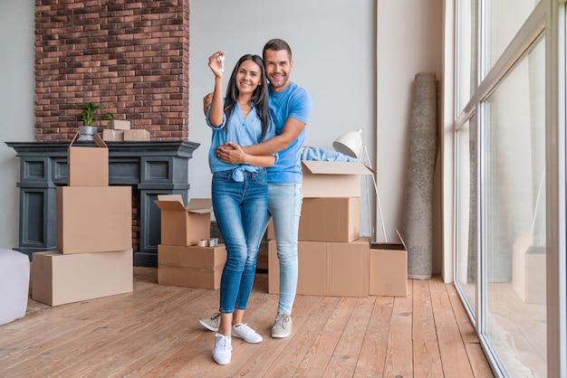 Retrato de pareja joven con llaves en apartamento nuevo