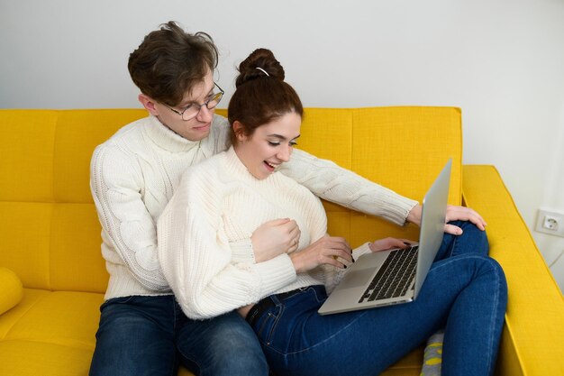 Retrato de una pareja joven sonriente que usa una computadora portátil en casa foto interior de alta calidad