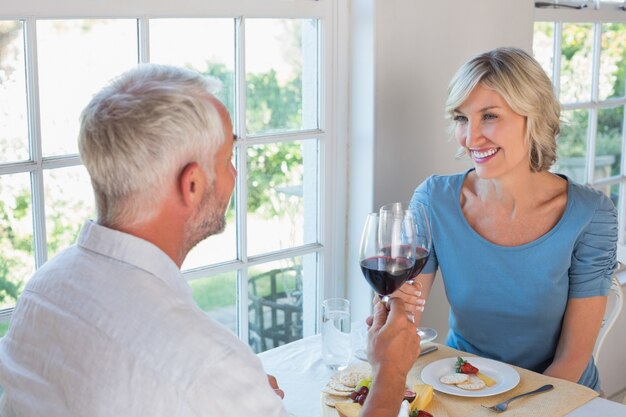 Retrato de una pareja madura brindando copas de vino sobre la comida