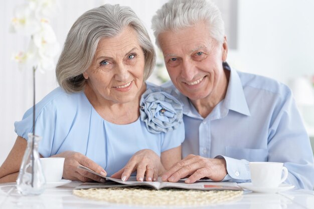 Retrato de pareja madura con revista bebiendo té