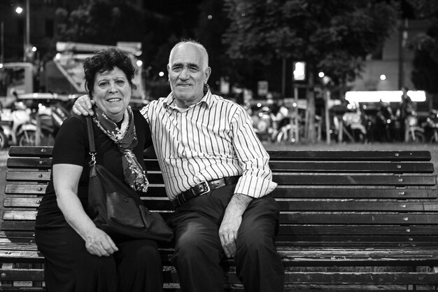 Foto retrato de una pareja mayor sentada en un banco por la noche