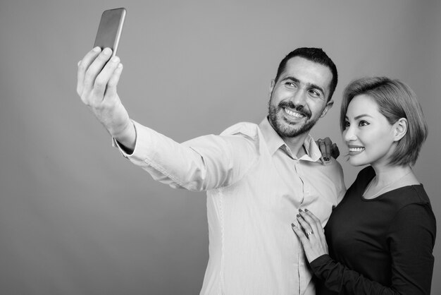 Retrato de pareja multiétnica juntos y enamorados en gris en blanco y negro