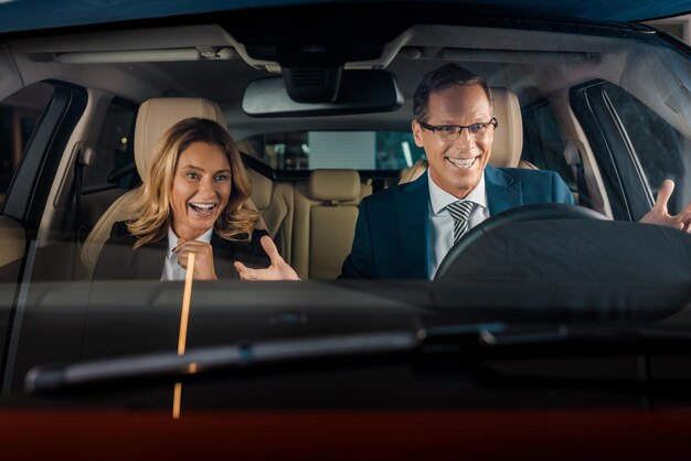 Retrato de pareja de negocios alegre en coche nuevo para prueba de conducción