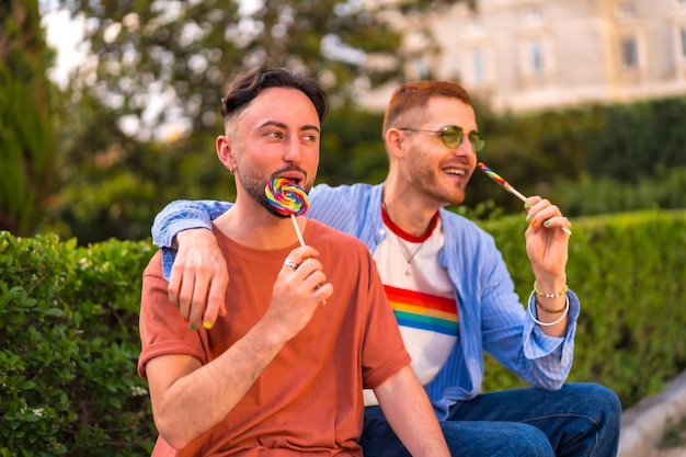 Retrato de pareja de novios sonriente comiendo una piruleta en el parque al atardecer en la ciudad Diversidad y concepto de estilo de vida lgbt