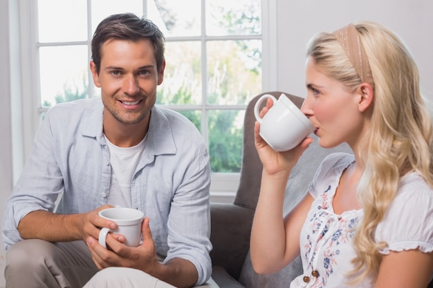 Retrato de pareja relajada con tazas de café en la sala de estar