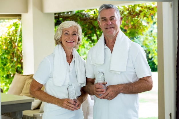 Retrato de pareja senior activa sosteniendo botellas de agua