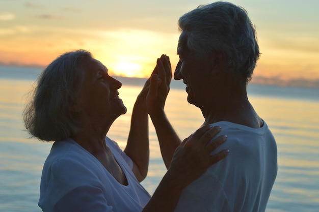 Retrato de pareja senior en el mar al atardecer