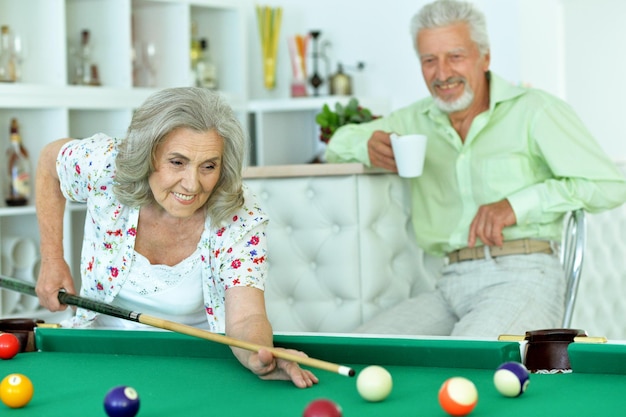 Retrato de una pareja senior sonriente jugando al billar juntos
