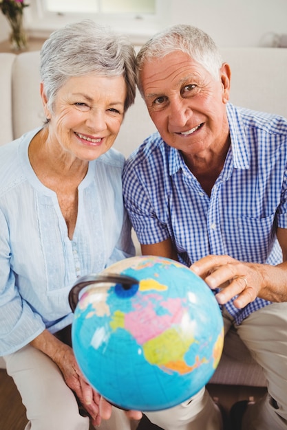 Retrato de pareja senior sosteniendo un globo y sonriendo en la sala de estar