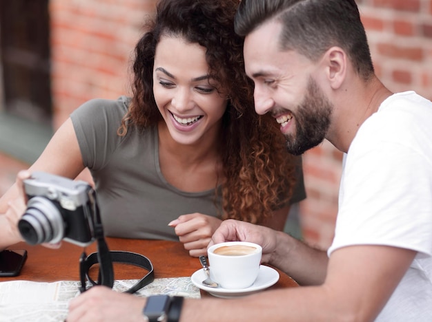 Foto retrato de una pareja sentada en un café y mirando fotos.