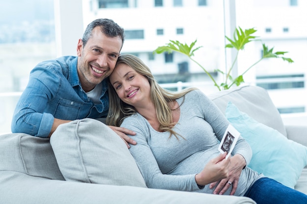 Retrato de pareja sentada en el sofá y con ecografía