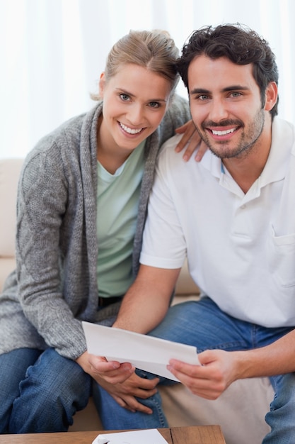 Retrato de una pareja sonriente leyendo una carta