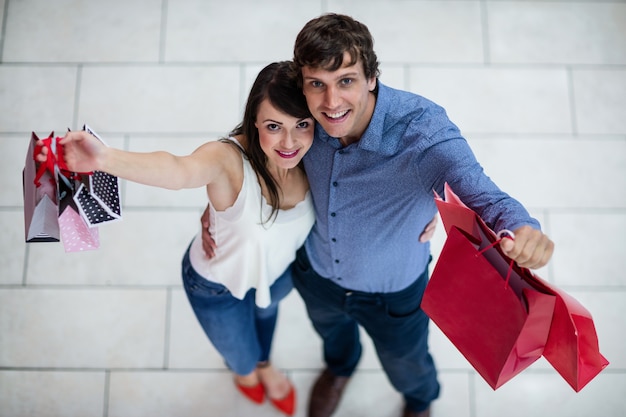 Retrato de pareja sonriente mostrando bolsas de compras