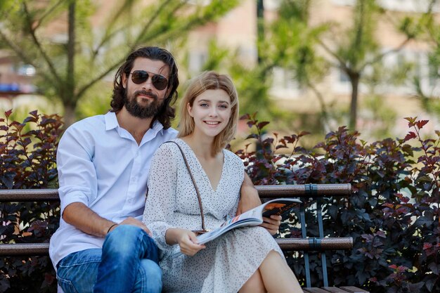 Foto retrato de una pareja sonriente sentada en un banco del parque