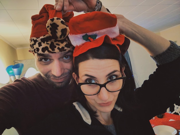 Foto retrato de una pareja sonriente con sombreros en casa