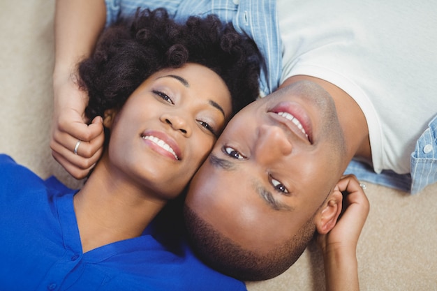 Retrato de una pareja sonriente tumbada en el suelo y mirando a la cámara