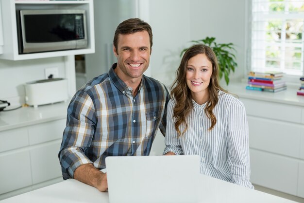 Retrato de pareja sonriente usando laptop en la sala de estar en casa