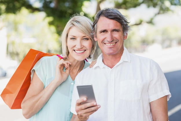 Retrato de pareja con teléfono celular y bolsas de compras