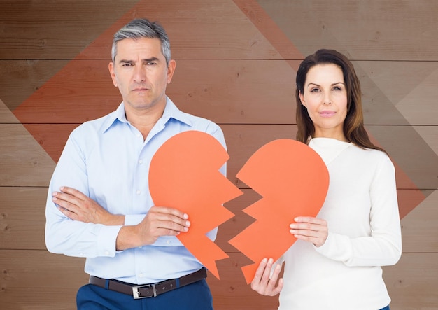 Retrato de pareja triste sosteniendo corazones rotos