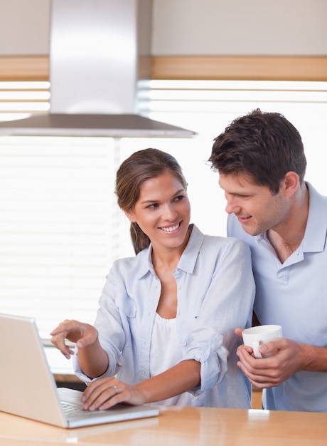 Retrato de una pareja usando una computadora portátil mientras toma el té