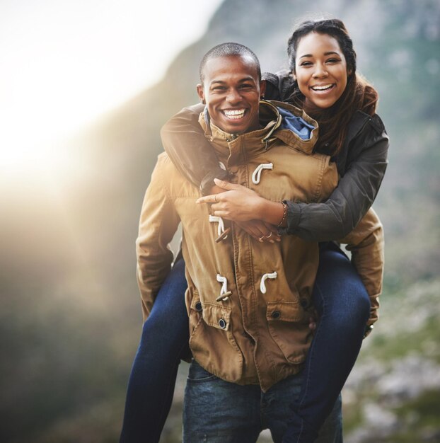 Retrato de pareja y viaje a espaldas en la naturaleza para aventuras románticas al aire libre y vacaciones Mujer hombre y sonrisa con amor por la montaña para el matrimonio conexión unión y viaje de excursión juntos