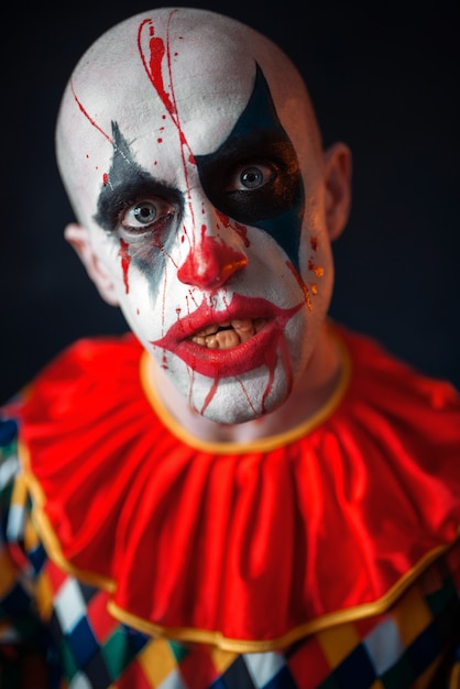 Retrato de payaso loco sangriento, cara en sangre. Hombre con maquillaje en disfraz de halloween, loco loco