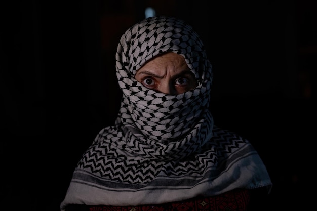 retrato de Pearson con keffiyeh blanco en fondo oscuro con expresión de ira en sus ojos debido a la violencia y contra la ocupación