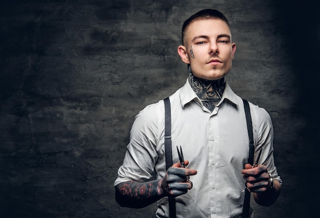 El retrato de un peluquero tatuado sostiene unas tijeras afiladas y una cuchilla.