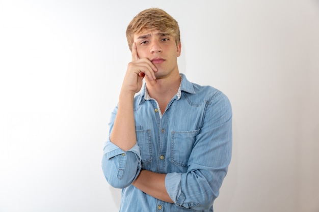 Retrato pensativo del hombre joven en el fondo blanco