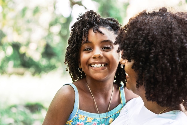 Retrato de una pequeña niña afroamericana mirando a la cámara sonriendo y feliz c