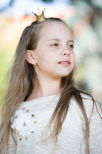 Retrato de una pequeña princesa linda feliz encantadora con el pelo largo y rizado rubio en un día soleado de verano