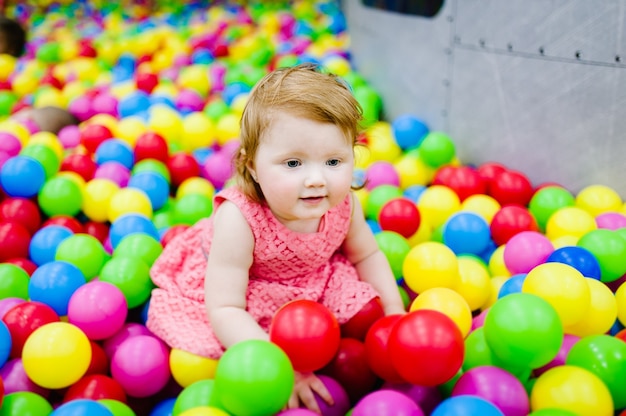 Retrato pequeno bebê fofo menina princesa infantil 1-2 anos em pé e brincar com balões, bolas coloridas no playground, piscina de bolinhas, piscina seca para festa de aniversário. Conceito de celebração do primeiro ano.