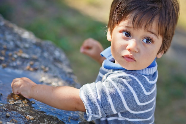 Retrato de un pequeño bebé guapo oriental jugando al aire libre en el parque