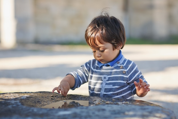 Retrato de un pequeño bebé guapo oriental jugando al aire libre en el parque