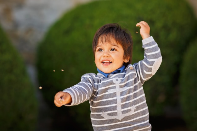 Retrato de un pequeño bebé guapo oriental jugando con guijarros al aire libre en el parque