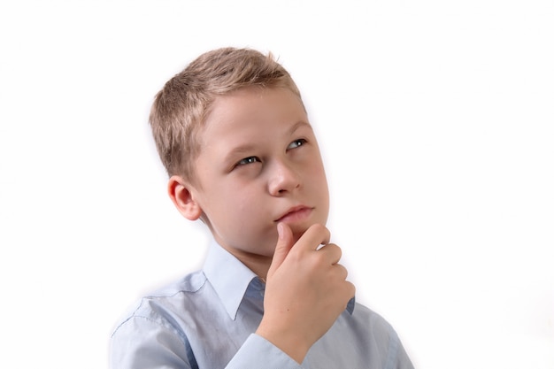 Retrato de un pequeño colegial en una pose pensativa aislado sobre fondo blanco.