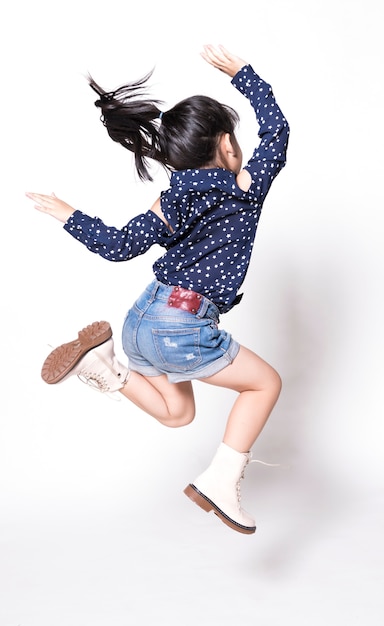 Retrato del pequeño salto asiático feliz del niño aislado en el fondo blanco