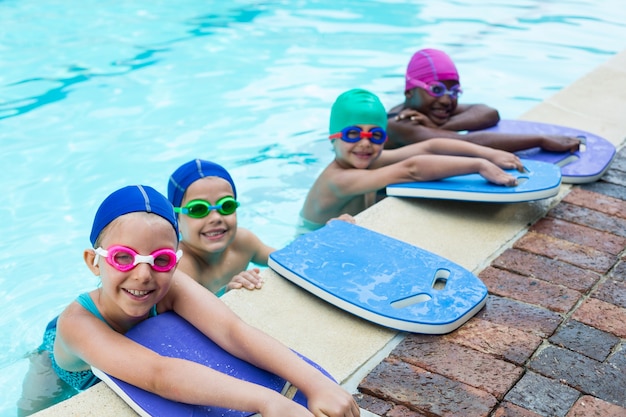 Retrato de pequeños nadadores con patinetas apoyado junto a la piscina