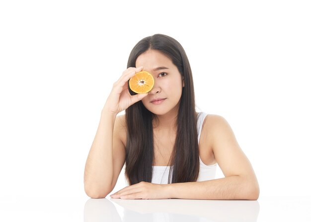 Retrato perfeito da pele fresca da bela jovem asiática com fatias de laranja na mão, isoladas no fundo branco