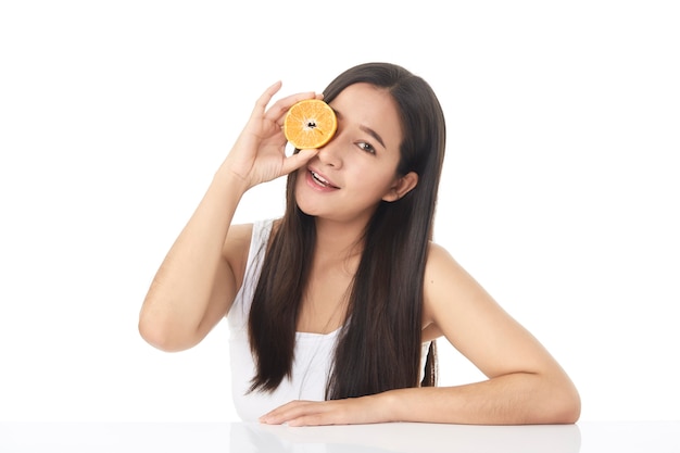 Retrato perfeito da pele fresca da bela jovem asiática com fatias de laranja na mão, isoladas no fundo branco