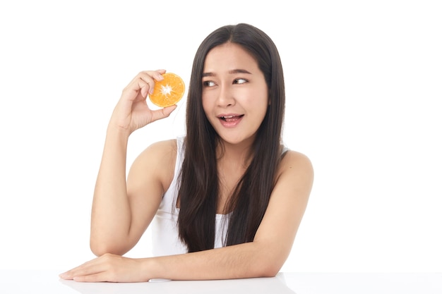 Retrato perfeito da pele fresca da bela jovem asiática com fatias de laranja na mão, isoladas no fundo branco