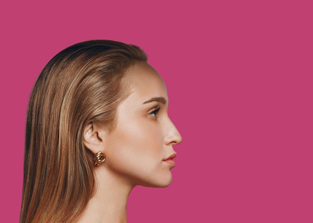 Retrato de perfil de belleza de mujer caucásica joven sobre fondo rosa