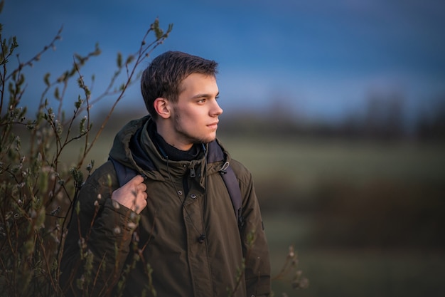 Retrato de perfil de un chico con una mochila en la naturaleza en el fondo del cielo nocturno