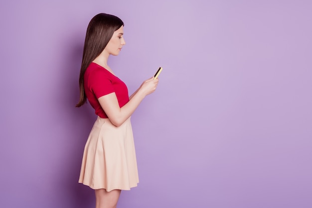 Retrato de perfil de dama impresionante mantenga teléfono navegando charlando sobre fondo púrpura
