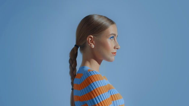 Retrato de perfil de una joven modelo en un estudio espacial azul con maquillaje colorido