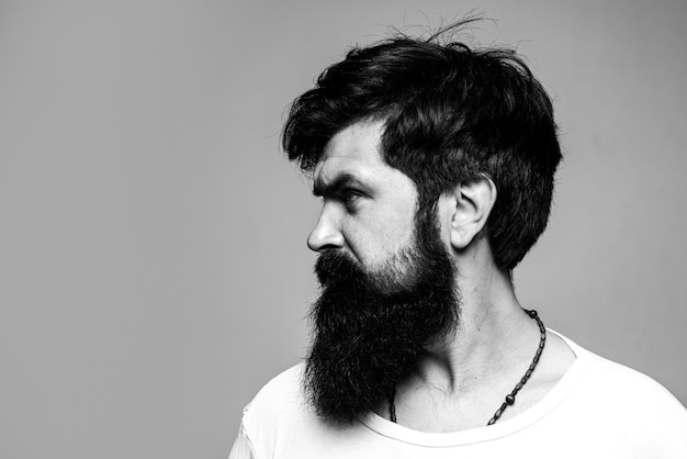 El retrato de perfil lateral medio vuelto de un hombre serio tiene barba y bigote se ve seriamente aislado en gris Expresión de tipo barbudo Hipster que parece un modelo masculino guapo