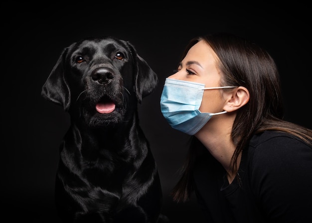 Retrato de un perro Labrador Retriever con una máscara médica protectora con una dueña