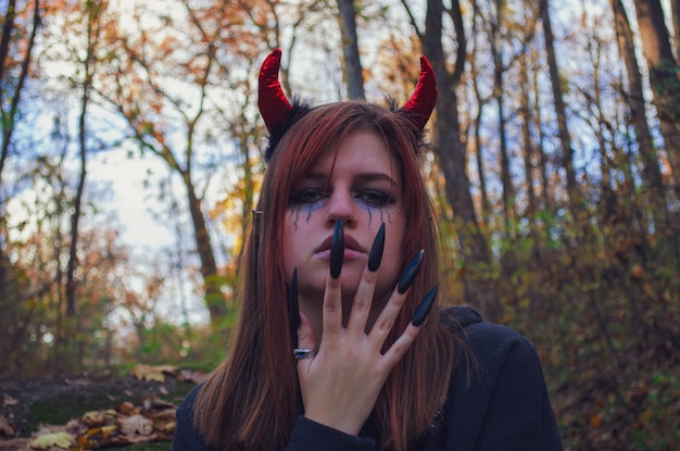 retrato de una persona en el bosque con cuernos rojos