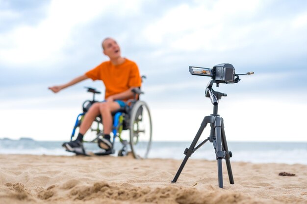 Retrato de una persona discapacitada en una silla de ruedas grabando un videoclip junto a la playa