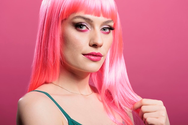 Retrato de una persona elegante con peluca rosa posando frente a la cámara, sintiéndose segura y despreocupada en el estudio. Atractiva mujer sensual con peinado glamuroso que muestra emociones elegantes.